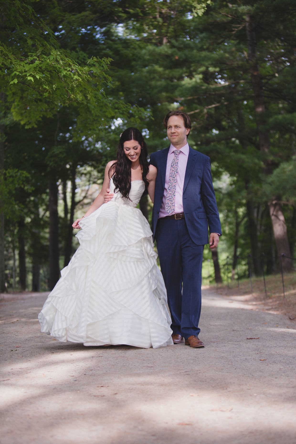 A natural portrait of a bride and groom walking in the Minute Man Park during their first look