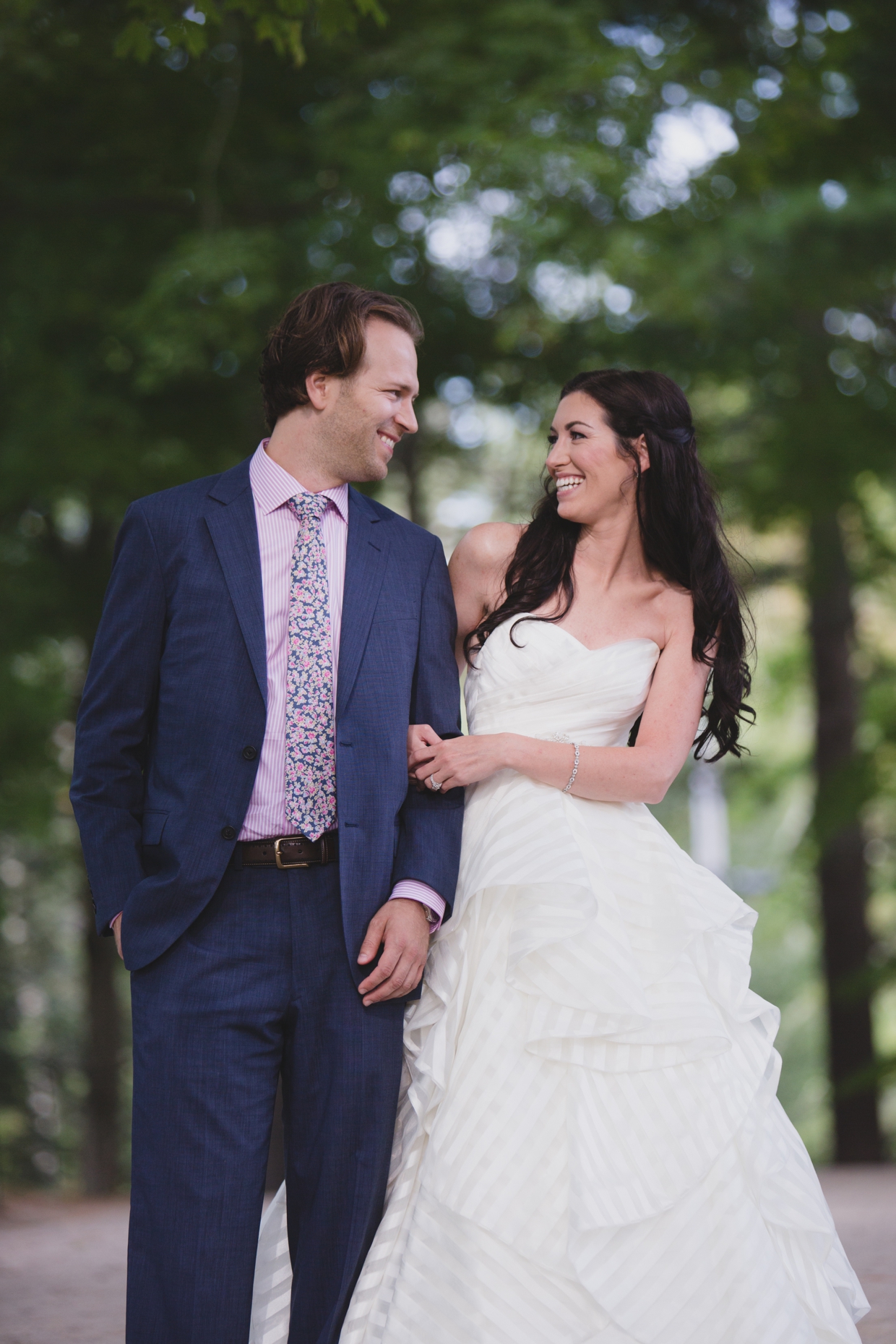 A natural and fun portrait of a bride and groom laughing as they walk through the Minute Man Park in Massachusetts