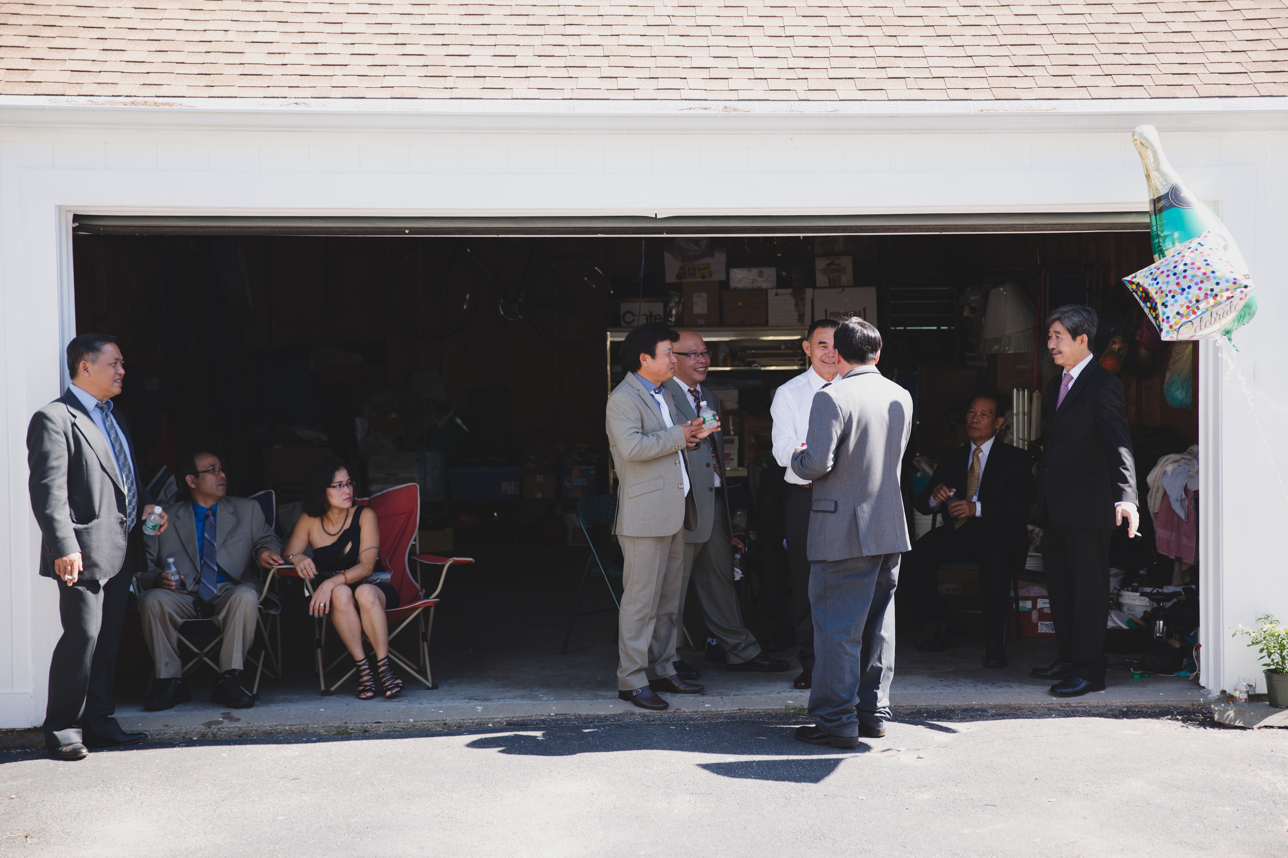 A documentary style photograph of guest talking and eating in a garage after a vietnamese tea ceremony in Boston