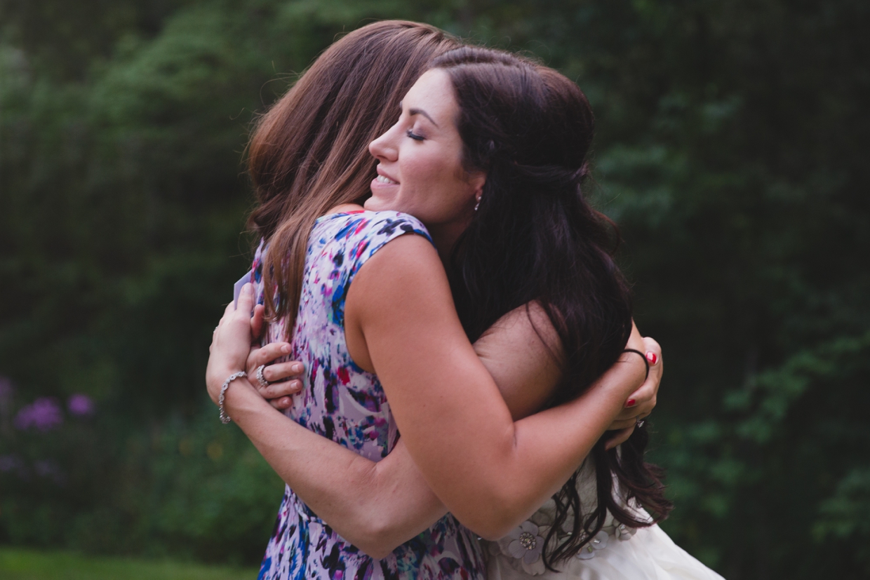 A bride hugs her friend after her wedding ceremony during a backyard wedding in Massachusetts