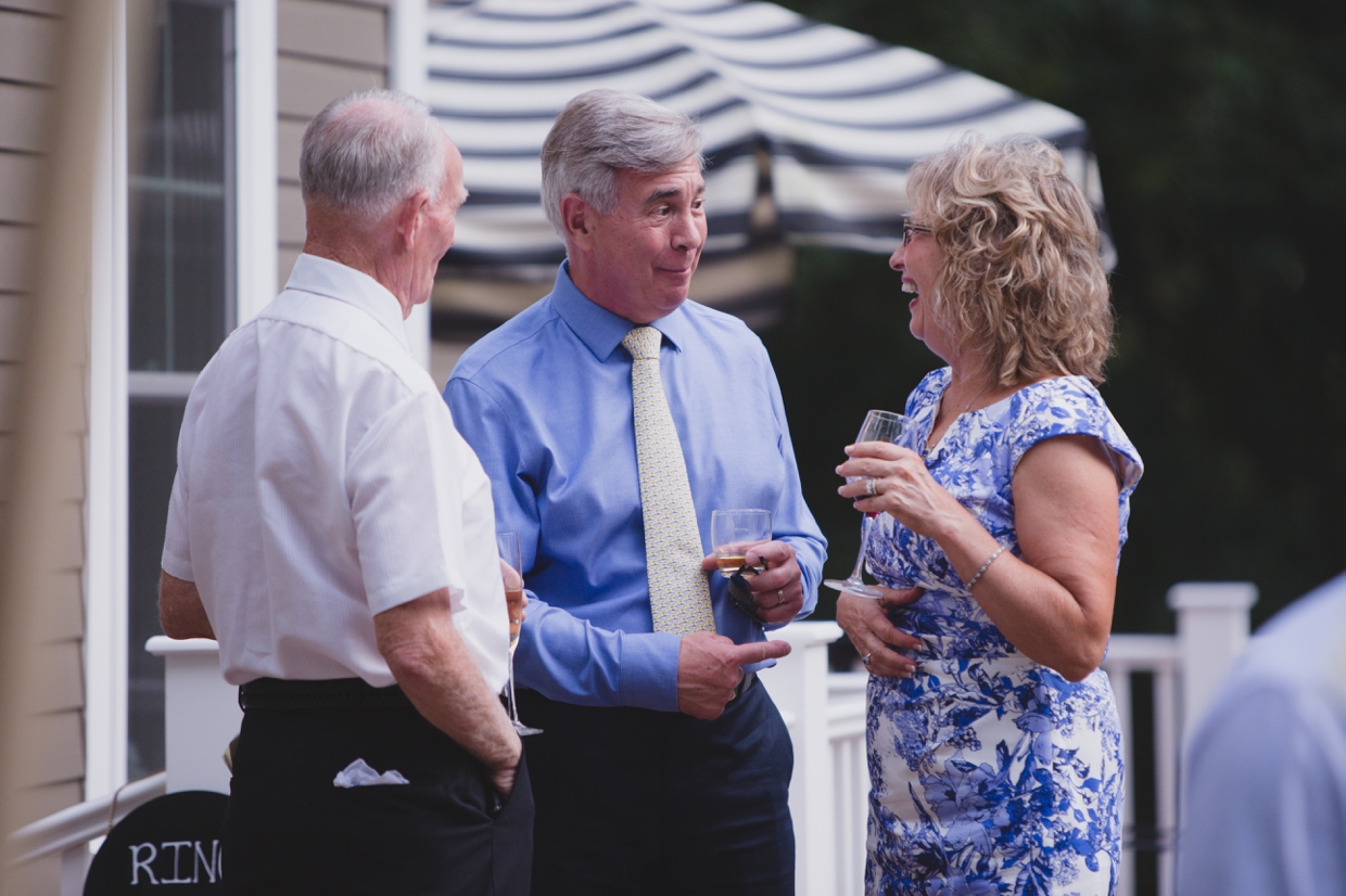 A candid photograph of guests talking and laughing during a backyard wedding in Massachusetts