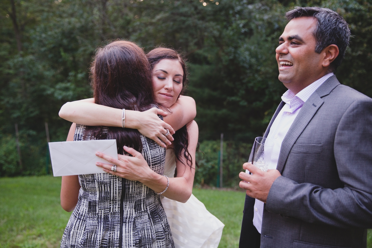 A candid photograph of a bride hugging her friend during her backyard wedding in Massachusetts