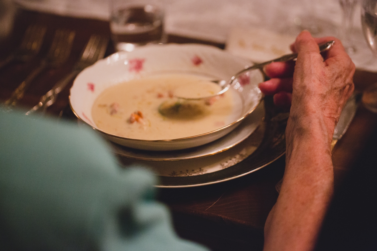A detailed photograph of the bride's grandmother eating soup made by Saltbox Farms during a backyard wedding in Massachusetts