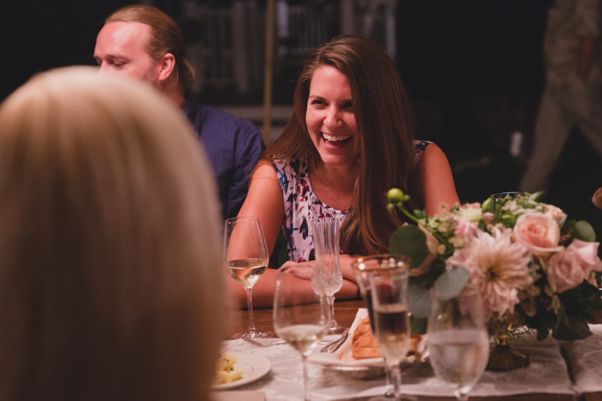 A candid photograph of a guest laughing during dinner at a backyard wedding in Massachusetts