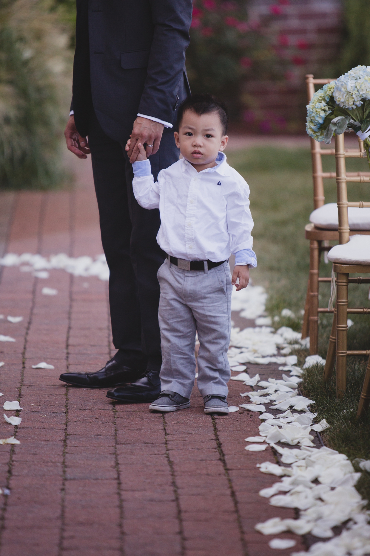 A candid photograph of a ring bearer holding his father's hand before a wedding ceremony at the Boston Marriott Hotel