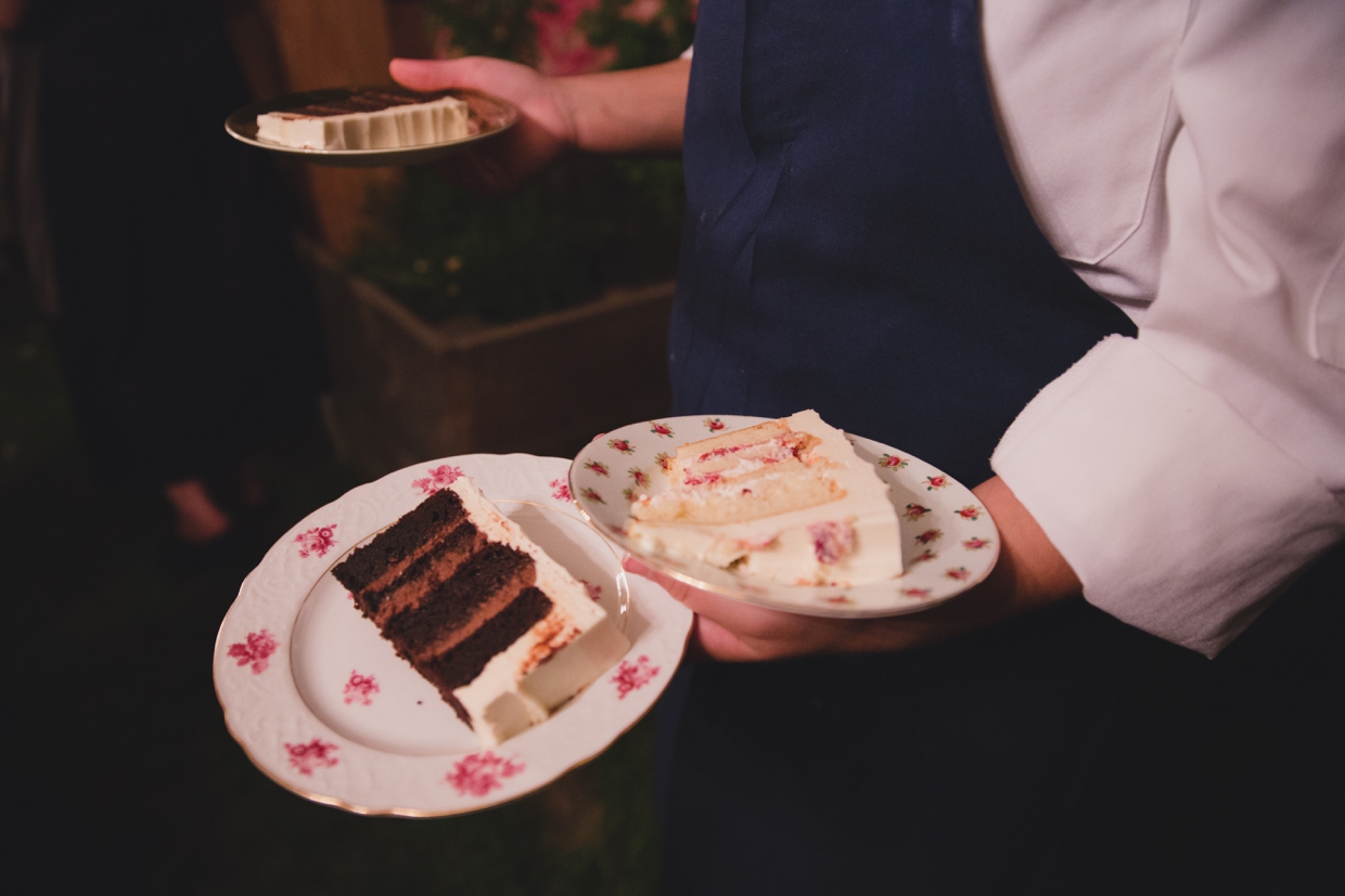 A documentary style photograph of the wedding cake being brought to the table during a backyard wedding in Massachusetts