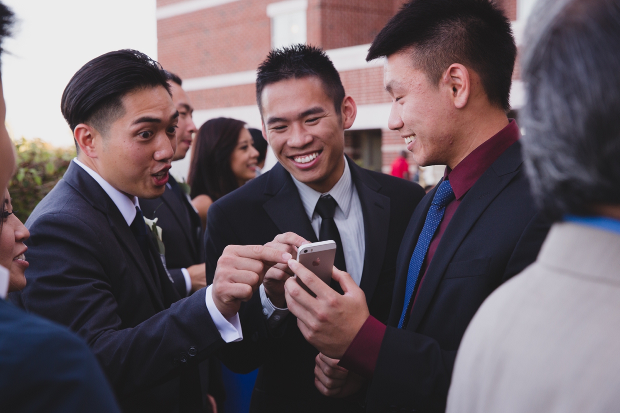 A candid photograph of guest laughing at a photograph on their phone during a wedding at the Boston Marriott Hotel