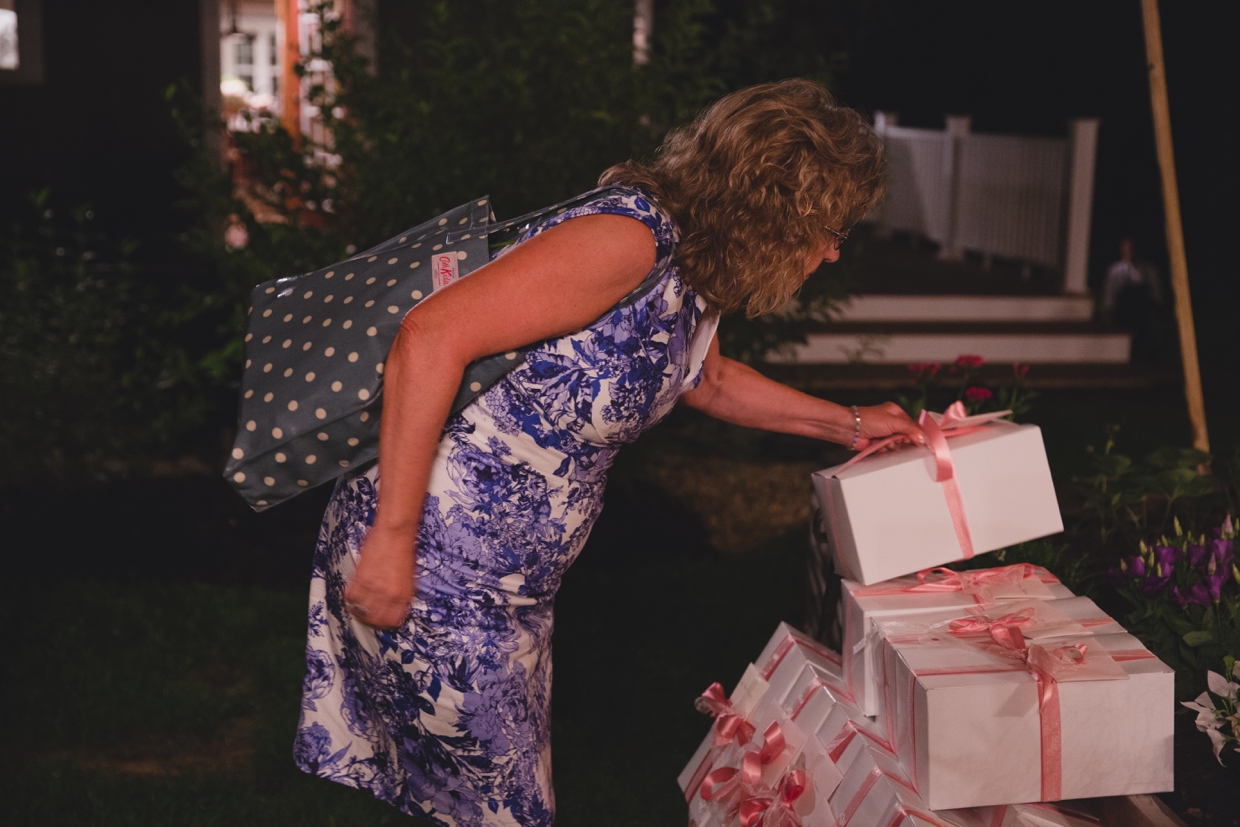 A mother of the groom takes her wedding gift as she leaves the backyard wedding in Massachusetts
