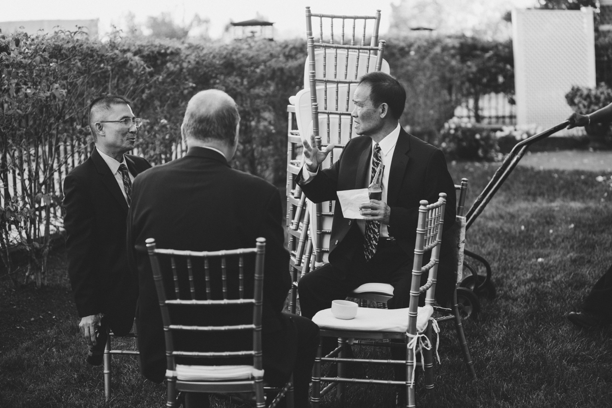 A documentary style photograph of three men talking during a wedding at the Boston Marriott Hotel