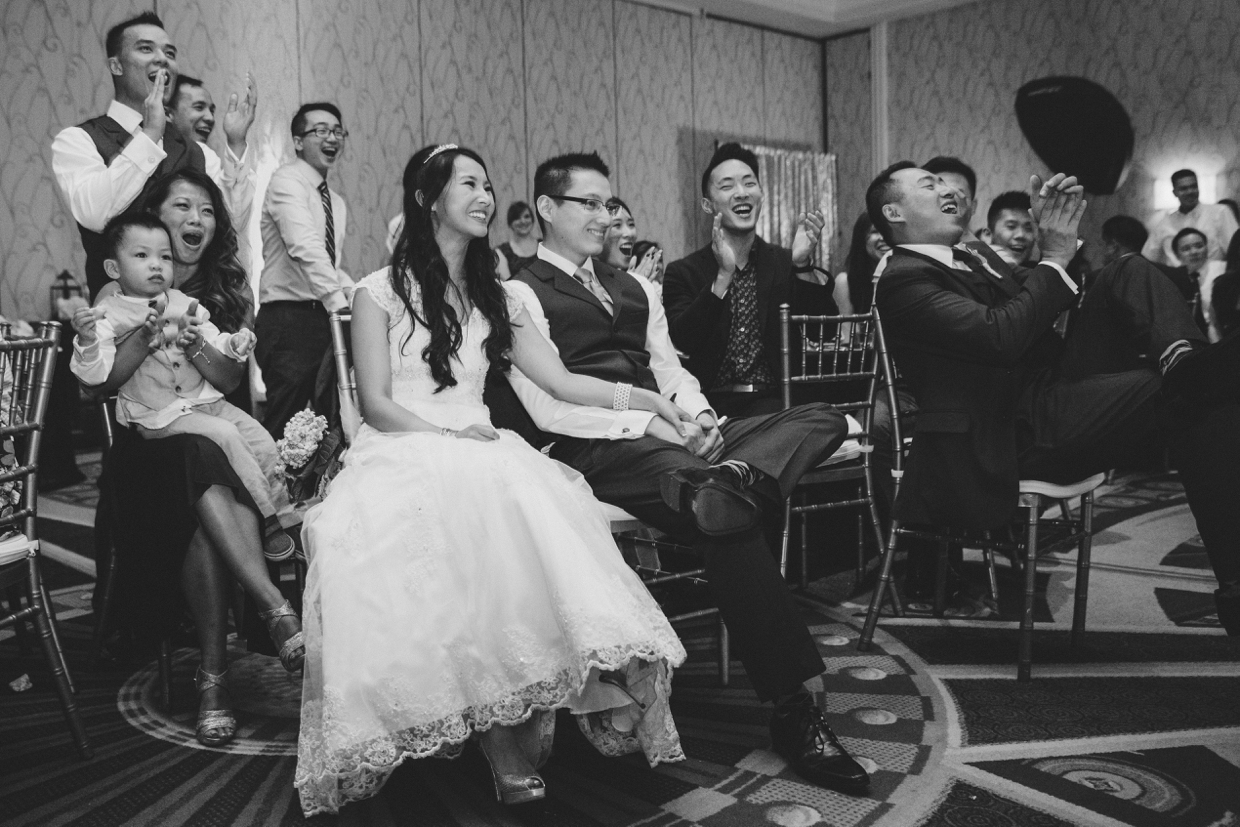 A documentary style photograph of the wedding party cheering and laughing during the wedding speeches at the Boston Marriott Hotel