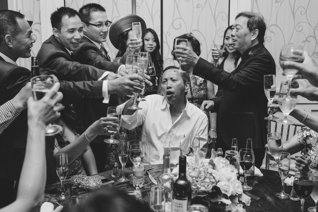 A documentary style photograph of guest raising their glass to toast the bride and groom during a wedding at the Boston Marriott Hotel
