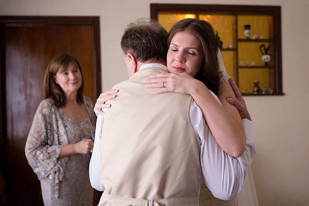 Documentary style photograph of a bride hugging her father on the morning of her wedding