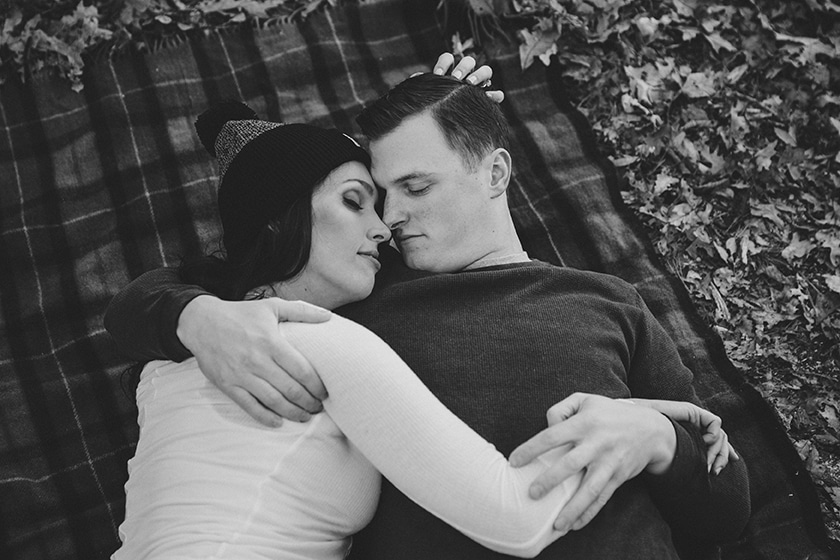 An intimate portrait of a couple laying together on a blanket at Boderland State Park during fall engagement session