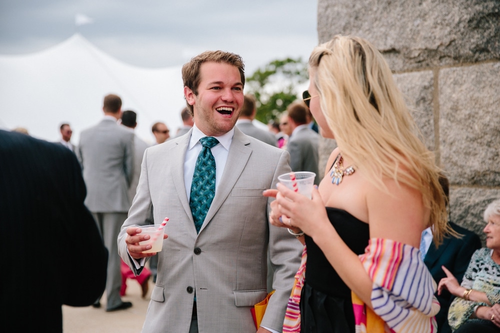 A photojournalistic photograph of wedding guests talking and laughing during a wedding at Pilgrims Monument in Provincetown, Cape Cod