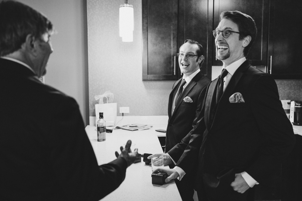 A documentary photograph of groom laughing with his groomsmen while getting ready for his wedding in Boston, Massachusetts