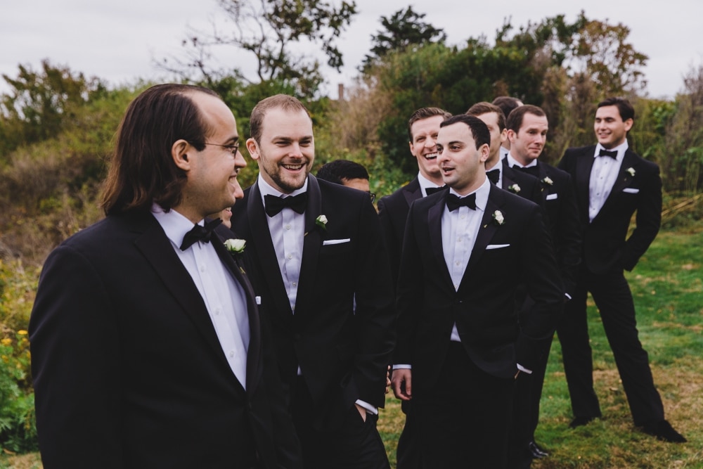 A documentary photograph of groomsmens talking and laughing during a wedding reception at the Castle Hill Inn in Newport, Rhode Island