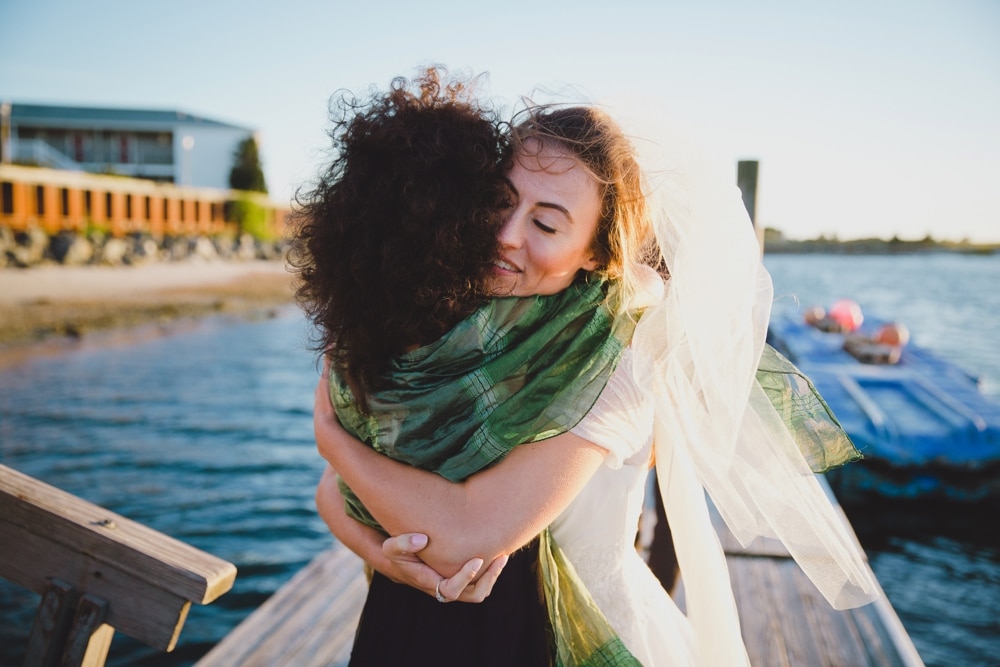 A documentary photograph of a bride hugging her friend during her wedding on Cape Cod