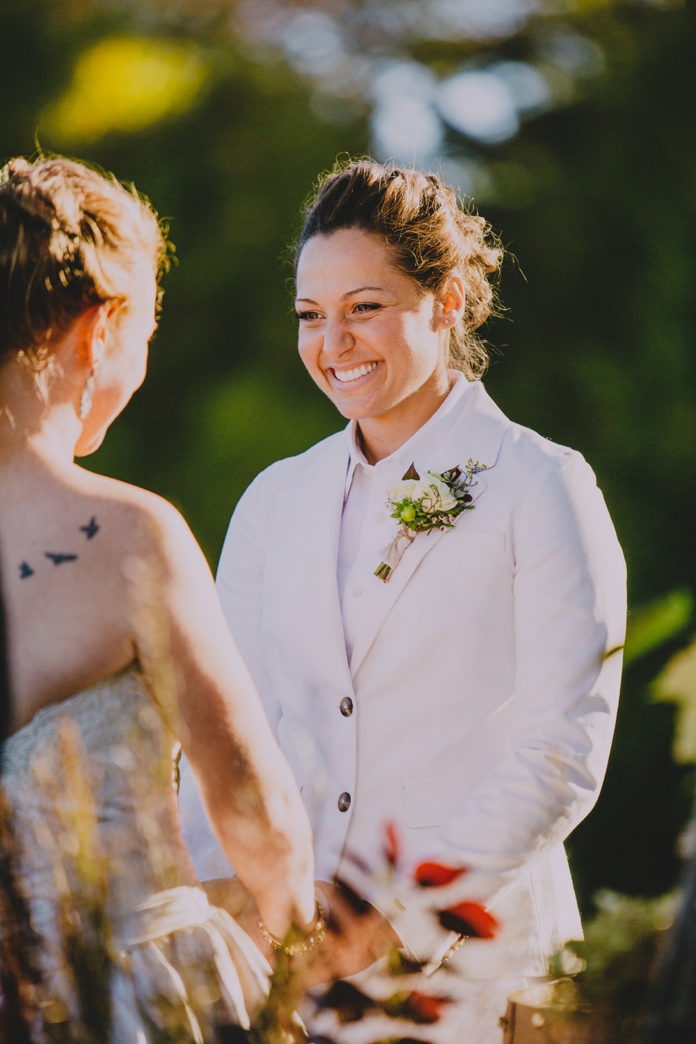A documentary photograph of a bride smiling at her bride during their rustic fall outdoor wedding ceremony at Kitz Farm in New Hampshire