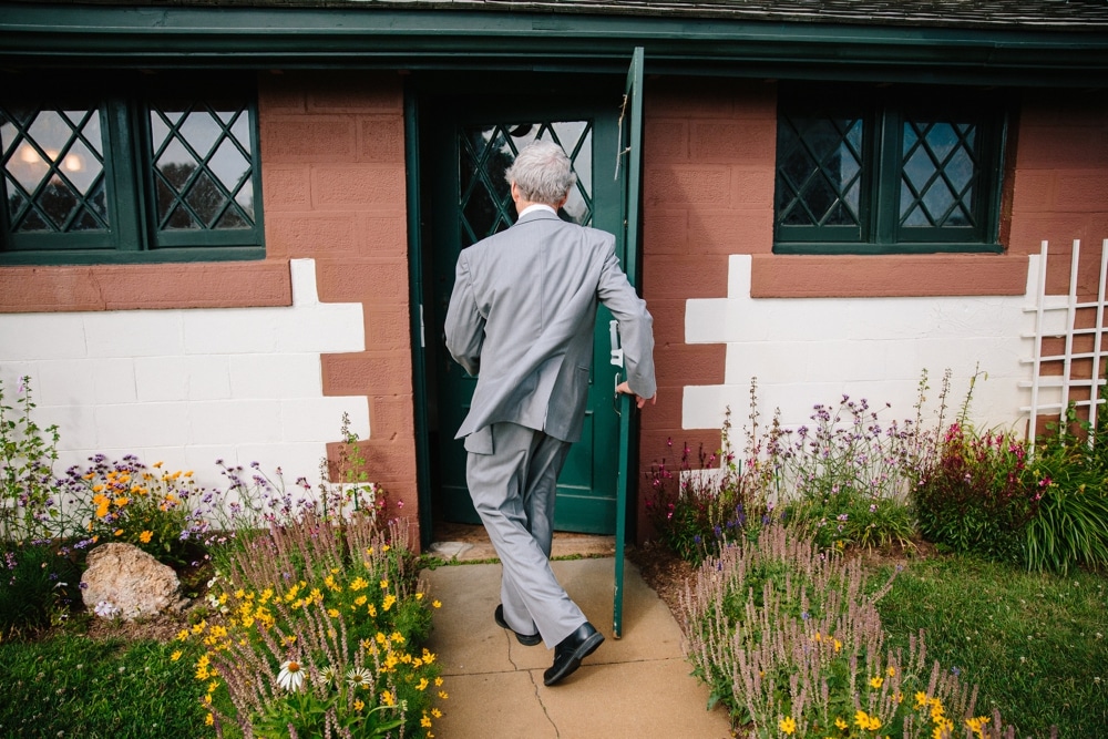 A photojournalistic photograph of the father of the bride running into his home before his daughters wedding at Pilgrims Monument in Provincetown, Cape Cod