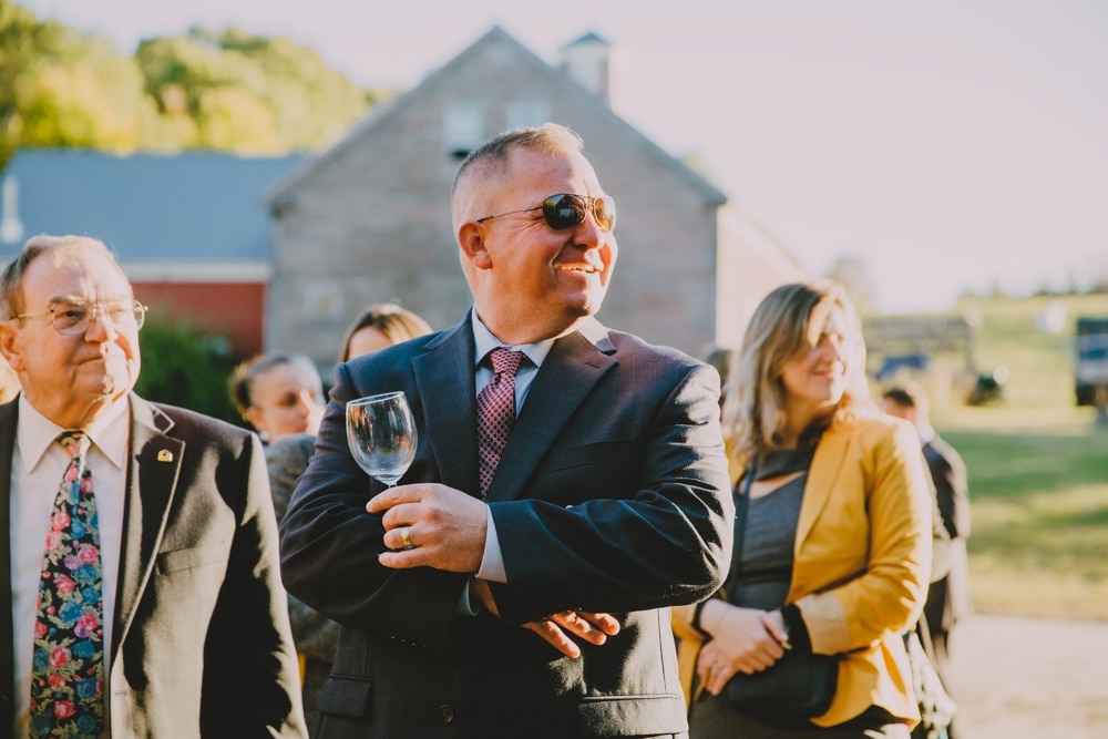 A documentary photograph of wedding guests enjoying the cocktail hour of a rustic barn wedding at New Hampshire's Kitz Farm