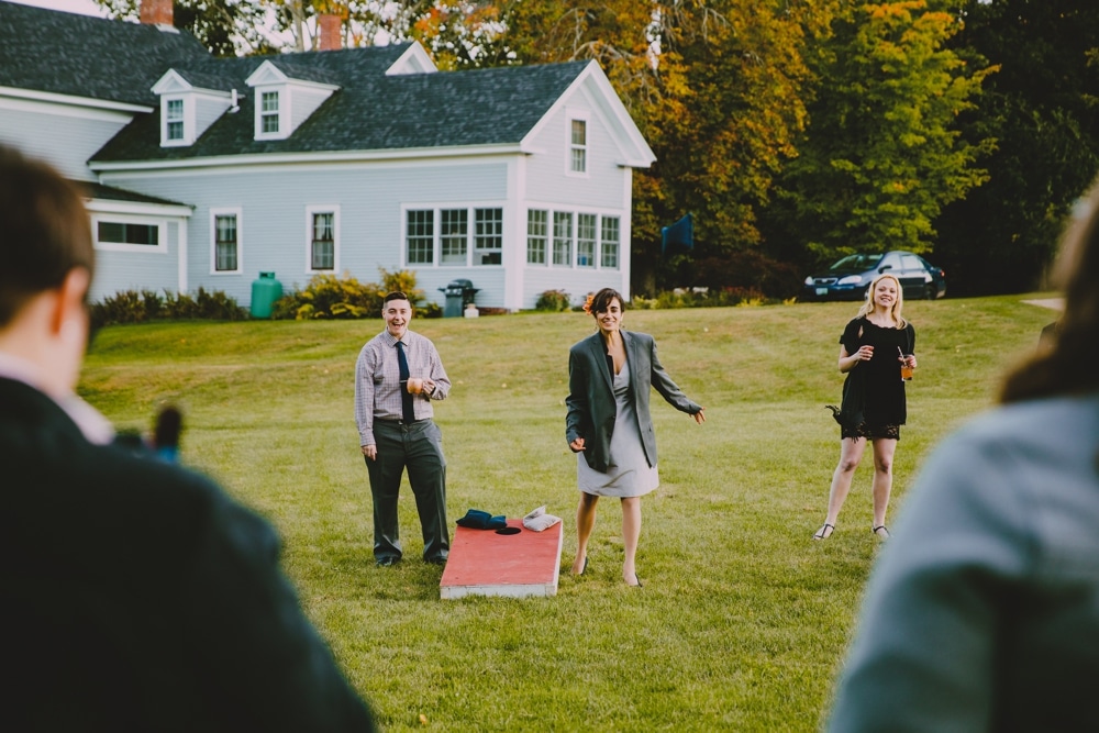 A documentary photograph of wedding guests playing lawn games during a rustic New Hampshire barn wedding at Kitz Farm