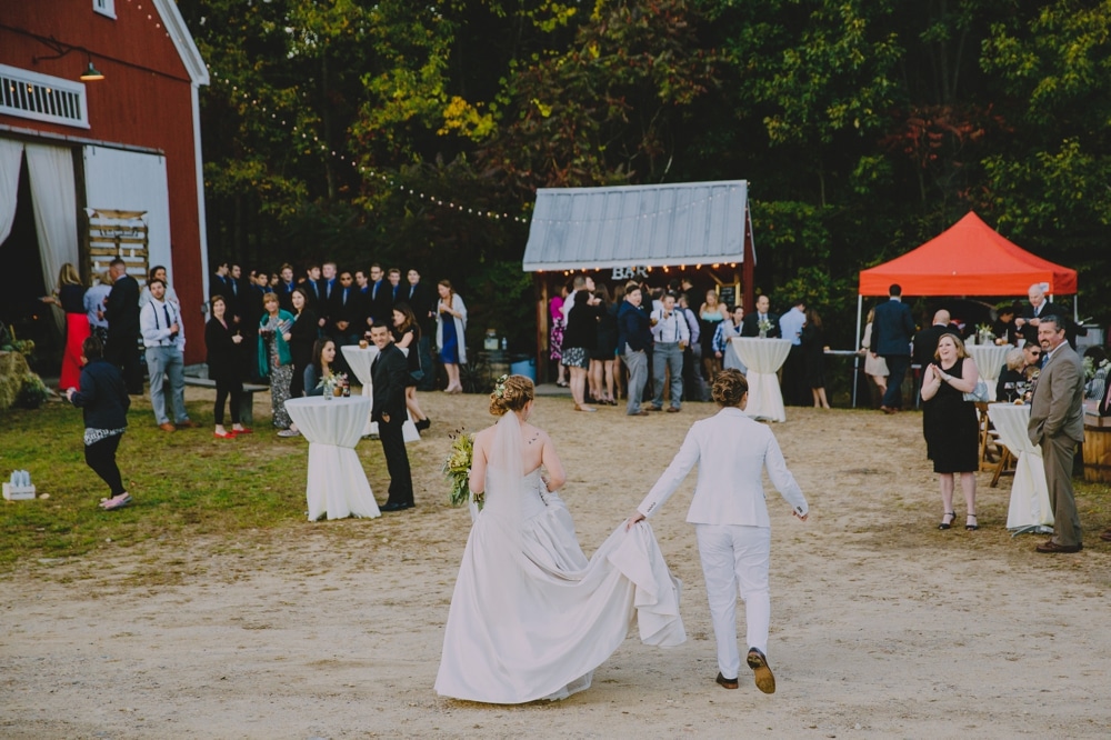 A documentary photograph of two brides entering their rustic DIY barn wedding reception at Kitz Farm in New Hampshire