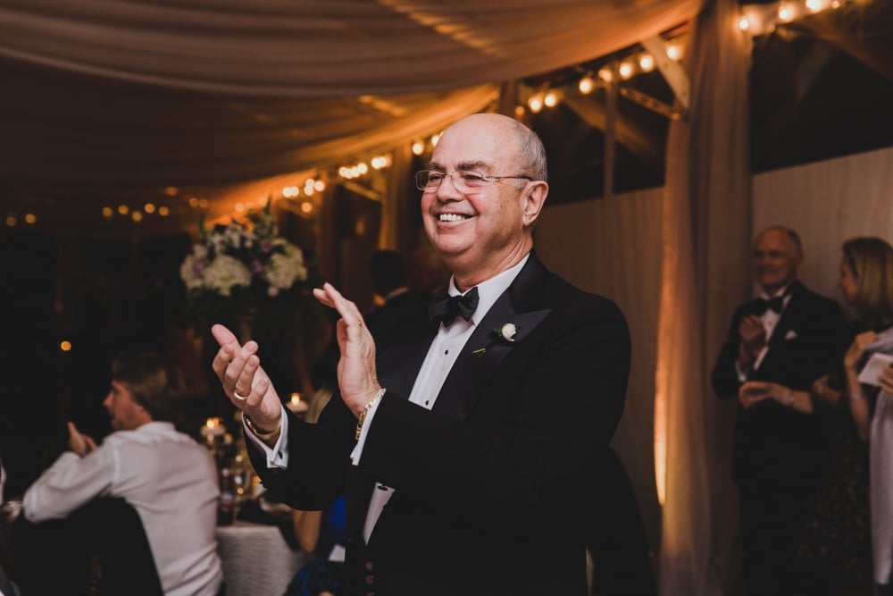 A father claps during the wedding toast of his son's wedding at the Castle Hill Inn in Newport, Rhode Island