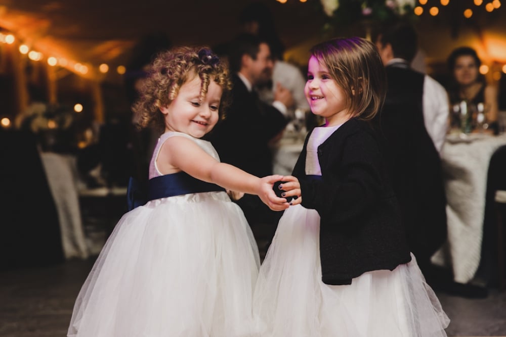 A documentary photograph of two flower girls dancing together at a Castle Hill Inn Wedding in Newport, Rhode Island