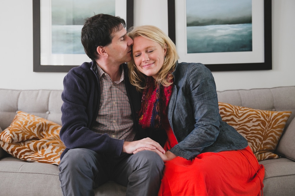 A sweet photograph of a husband kissing his wife during their in home lifestyle family photo session in Boston, Massachusetts