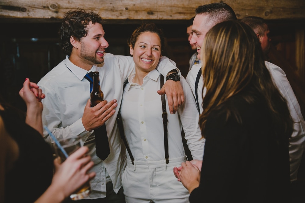 A documentary photograph of a bride talking and laughing with friends at her rustic wedding on Kitz Farm in New Hampshire
