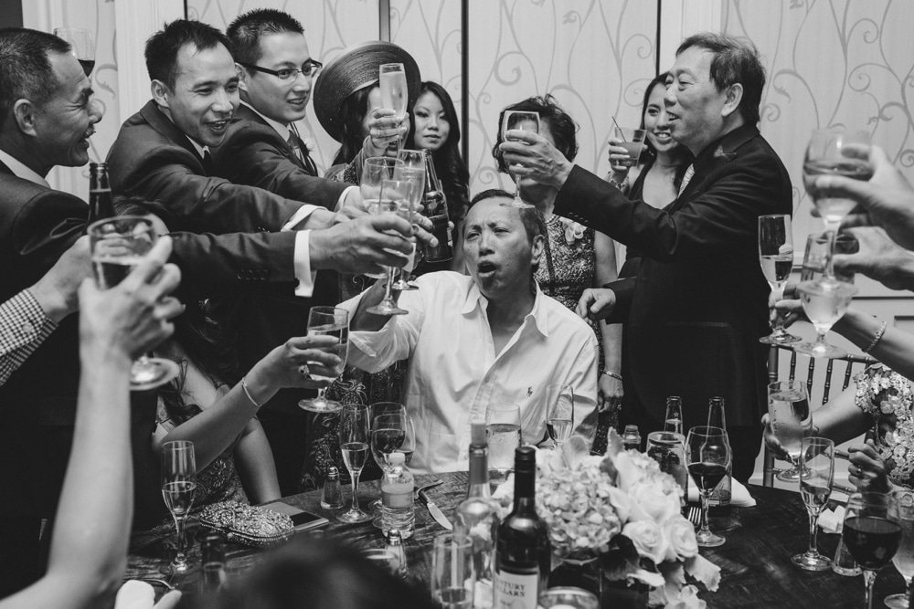 A documentary photograph of wedding guest toasting the bride and groom during a vietnamese wedding in Boston Massachusetts