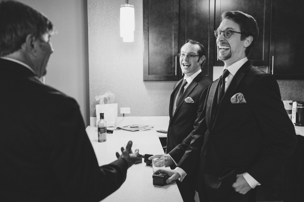 A photojournalistic photograph of a groom laughing with his groomsmen while getting ready for his wedding at the Oceanview of Nahant in Massachusetts