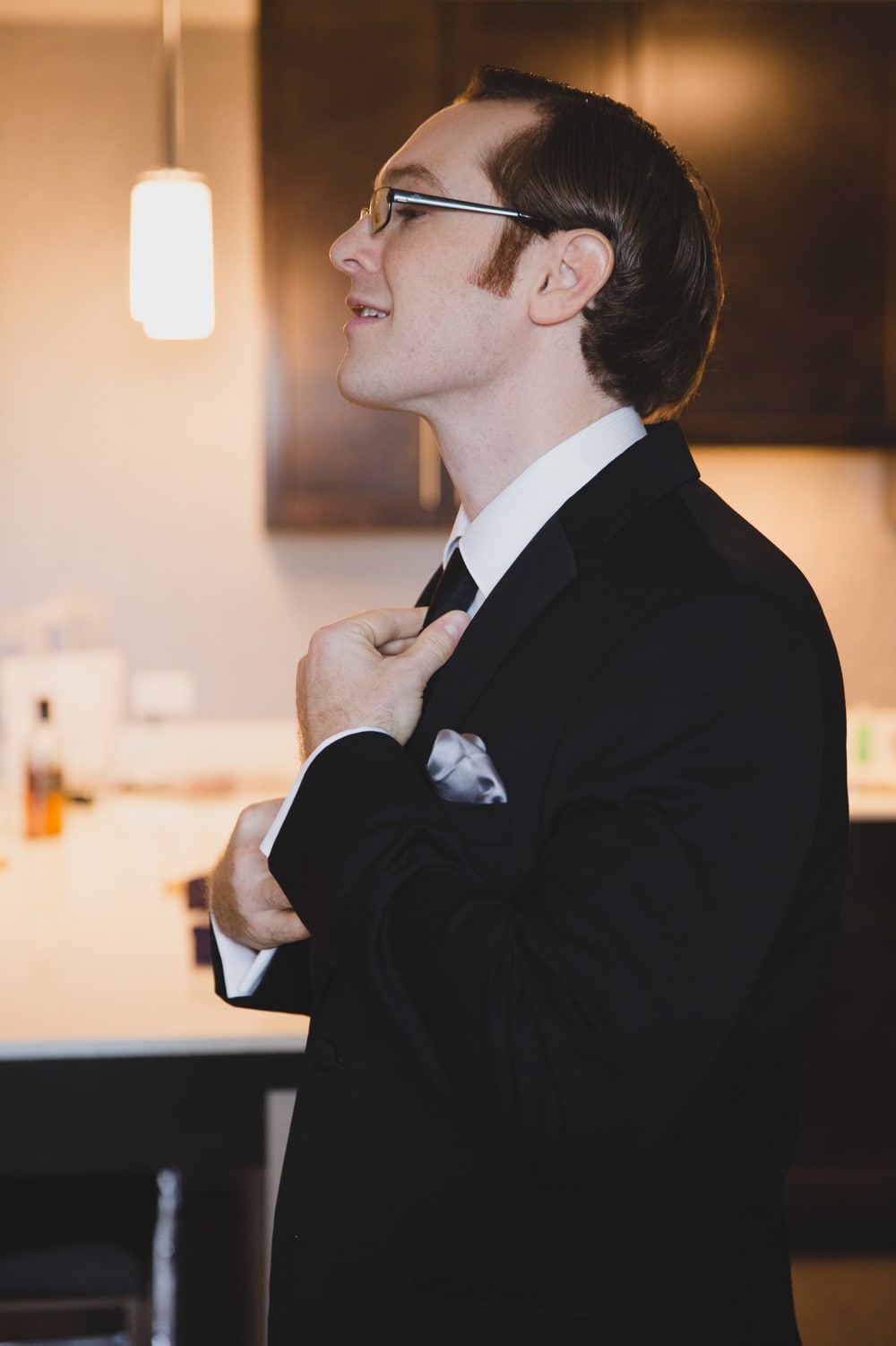 A documentary photograph of a groom fixing his tie while he gets ready for his wedding at the Oceanview of Nahant in Massachusetts