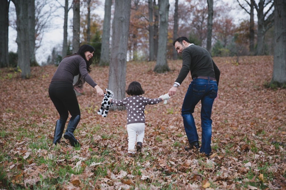A lifestyle photograph of a family playing in the Arnold Arboretum during their fall mini session in Boston, Massachusetts