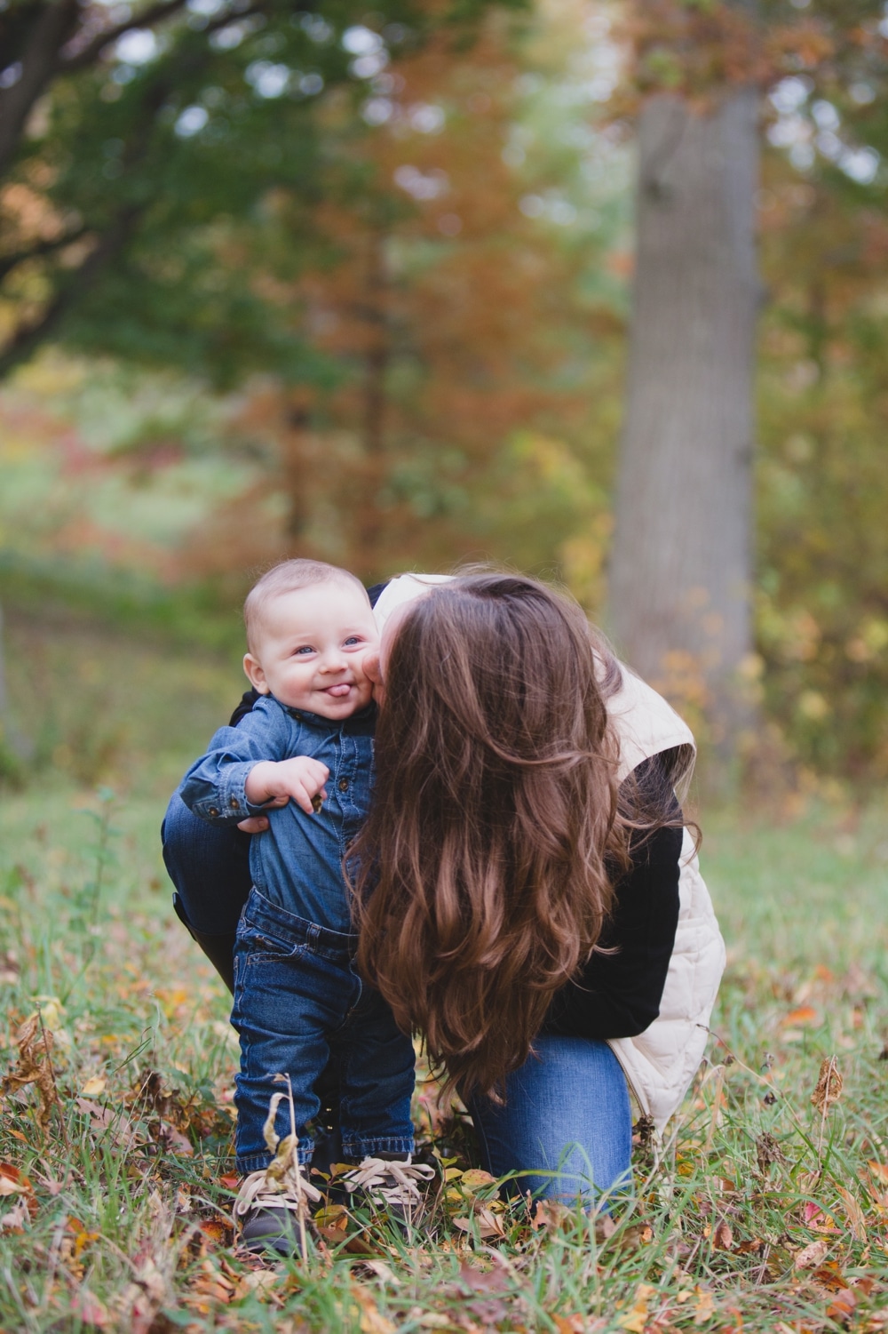 A photojournalistic photograph of a mother kissing her baby boy during a lifestyle mini session at Boston's Arnold Arboretum in Massachusetts