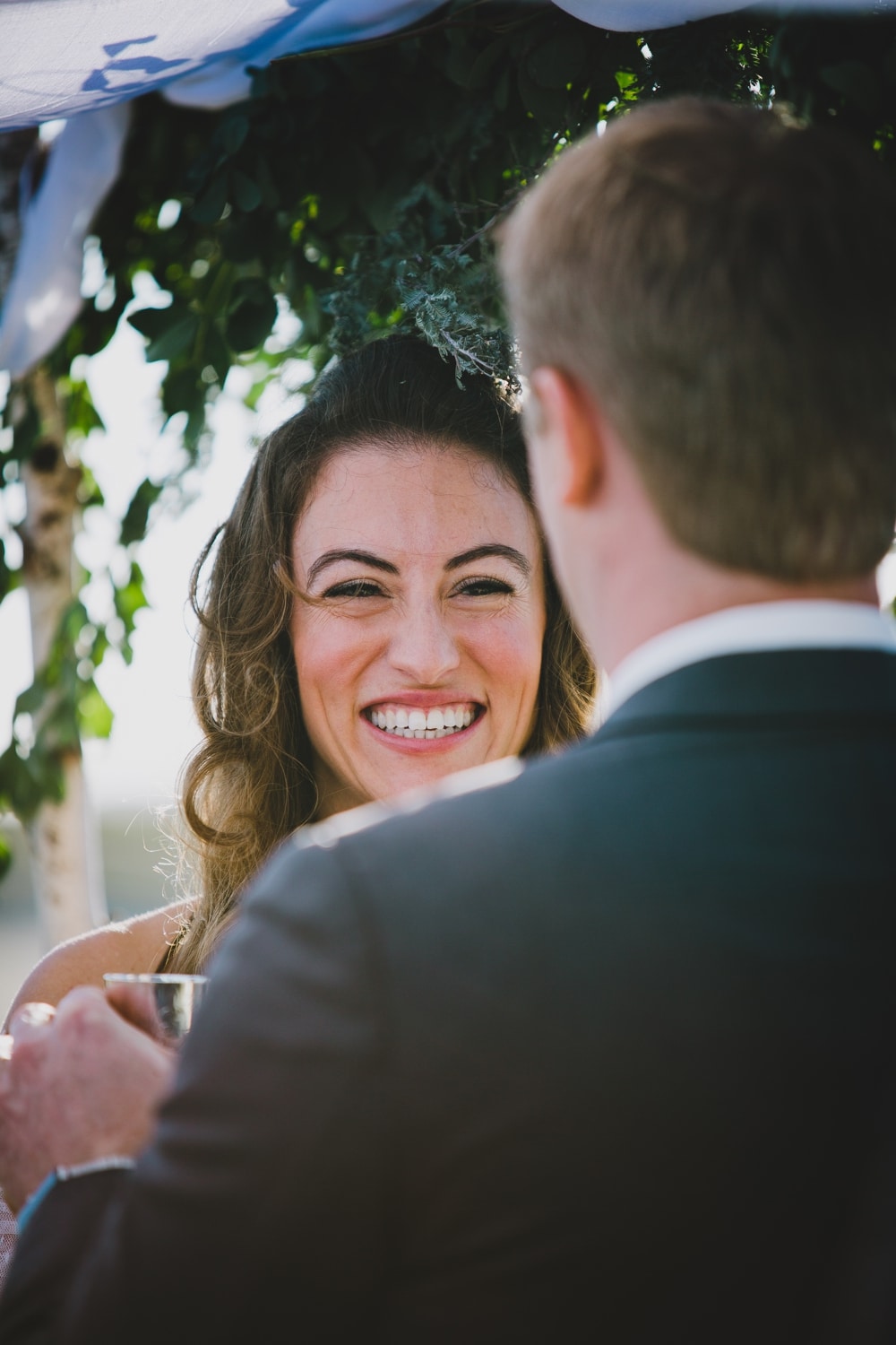 A documentary portrait of a bride smiling during an outdoor Jewish wedding ceremony in Cape Cod, Massachusetts
