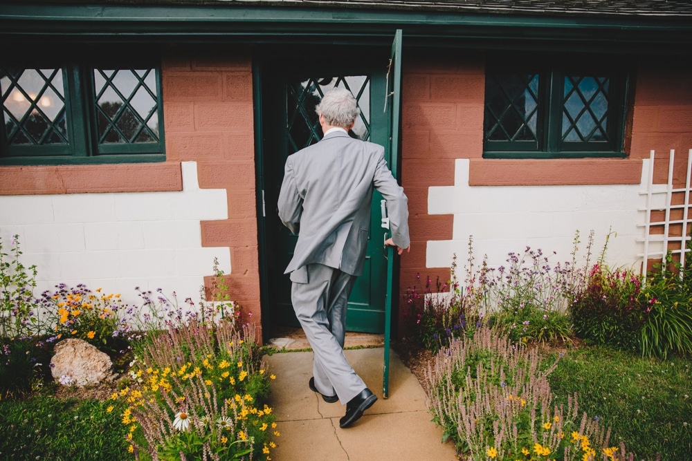 A fun photojournalistic photograph of the father of the bride running into the house before an outdoor wedding ceremony at Cape Cod's Pilgrim's Monument in Provincetown, Massachusetts