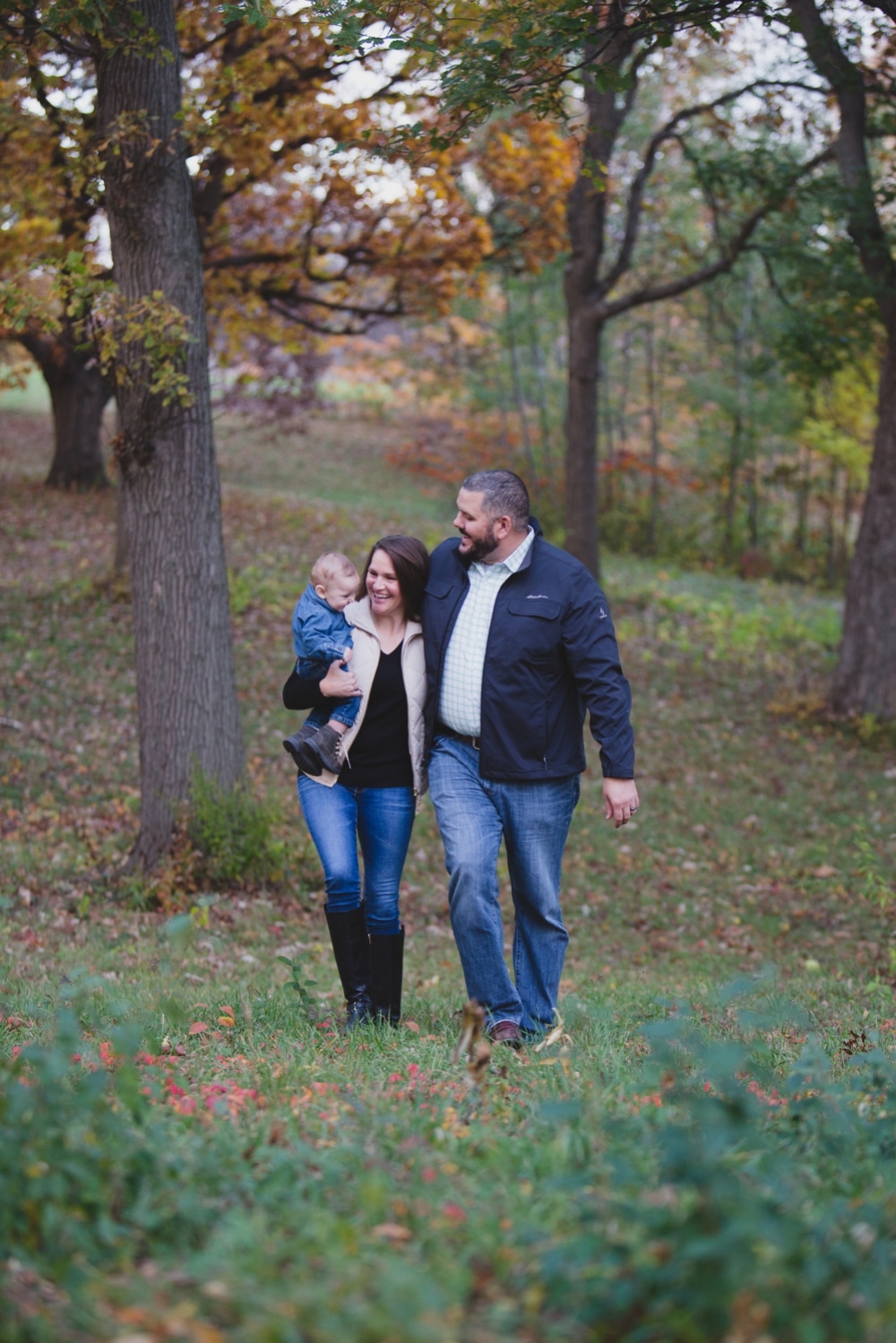 A lifestyle photograph of a family walking through the Arnold Arboretum during their fall family mini session in Boston, Massachusetts