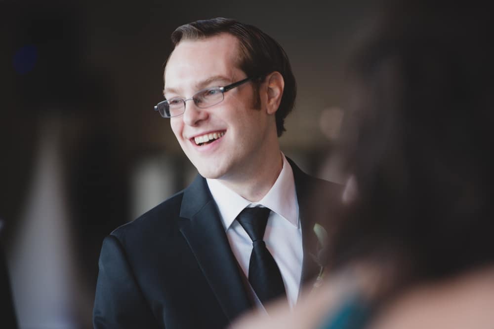 A documentary photograph of a groom smiling during his intimate wedding ceremony at the Oceanview of Nahant in Massachusetts