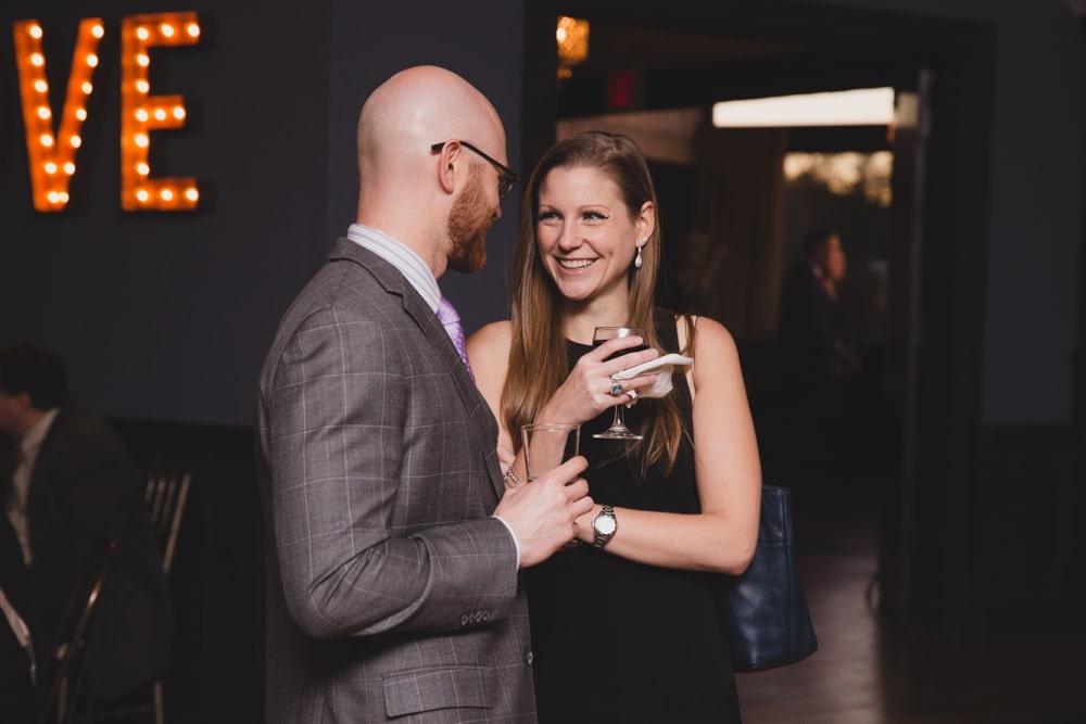 A photojournalistic photograph of wedding guests talking and laughing during an intimate cocktail hour at a Massachusetts Wedding at the Oceanview of Nahant