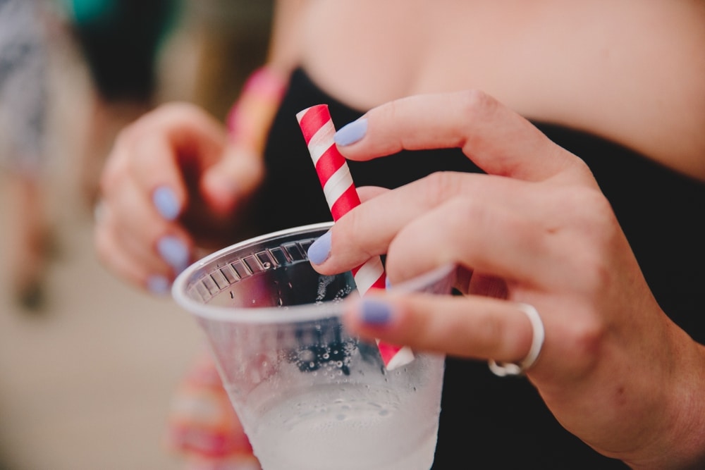 A photojournalistic photograph of a wedding guest holding a cocktail during a fun summertime wedding at Cape Cod's Pilgrim's Monument in Provincetown, Massachusetts