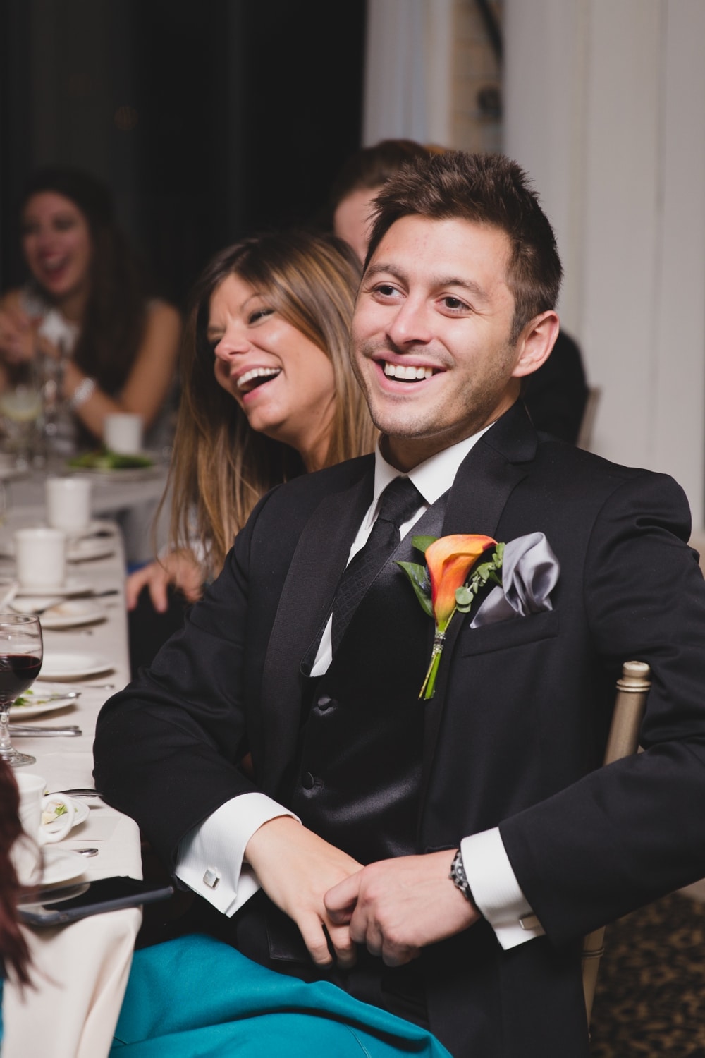 A photojournalistic photograph of wedding guests laughing during the wedding speeches at at intimate Oceanview of Nahant Wedding in Massachusetts