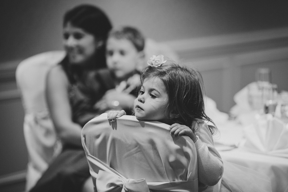 A documentary photograph of a flower girl watching the bride and groom dance during their summer wedding on Cape Cod