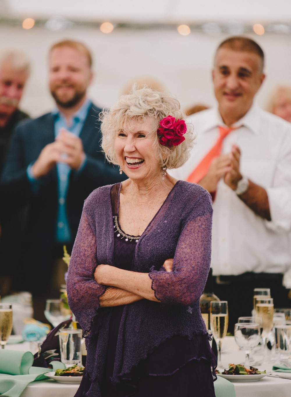 A photojournalistic photograph of a mother of the bride laughing during the wedding speeches at a fun, summertime Cape Cod wedding at Pilgrim's Monument in Provincetown, Massachusetts
