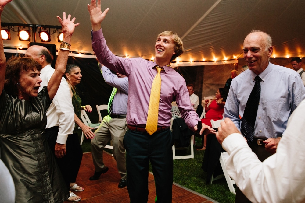 A photojournalistic photograph of wedding guests dancing during a fun, summertime Cape Cod wedding at the Pilgrim's Monument in Provincetown, Massachusetts