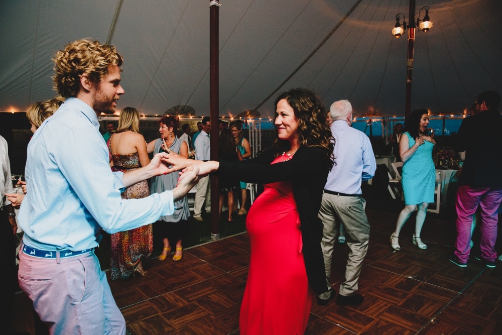 A photojournalistic photograph of wedding guests dancing during a fun, summertime, Cape Cod wedding at the Pilgrim's Monument in Provincetown, Massachusetts