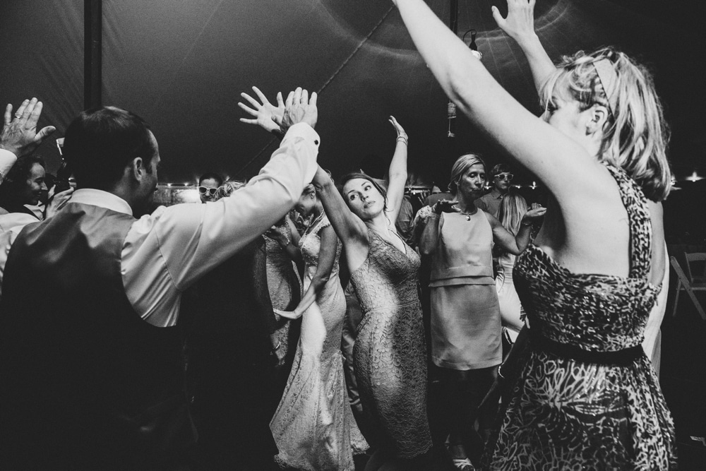 A documentary photograph of wedding guests dancing during a fun, summertime, Cape Cod wedding at the Pilgrim's Monument in Provincetown, Massachusetts