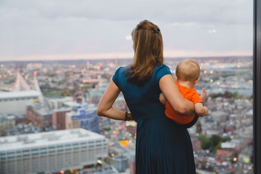 A photojournalistic photograph of a mother and baby enjoying the view at a State Room Wedding in Boston
