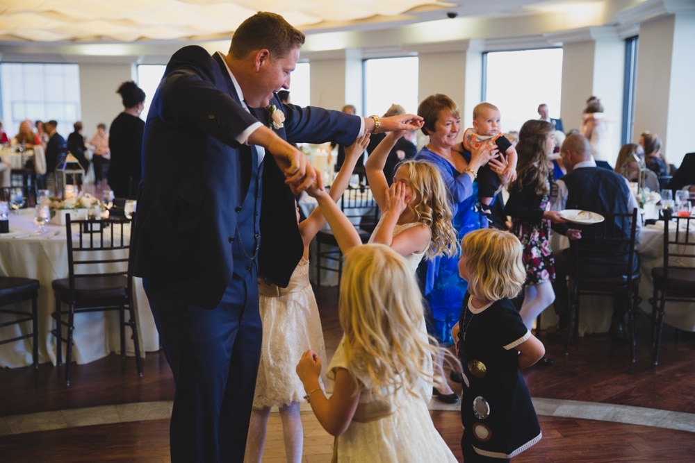 A photojournalistic photograph of a groom dancing with the flower girls at his State Room Wedding in Boston