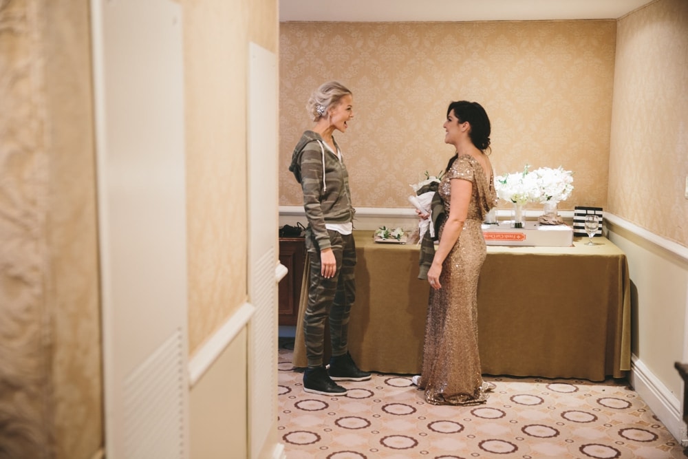 A documentary photograph of a bride smiling at her bridesmaid while they get ready for a Taj Boston Hotel wedding